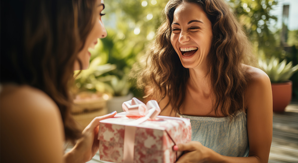 Uśmiechnięta kobieta wręcz przyjaciółce prezent