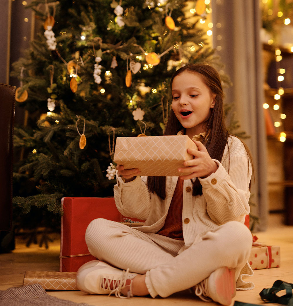 Dziewczynka cieszy się z prezentu pod choinką