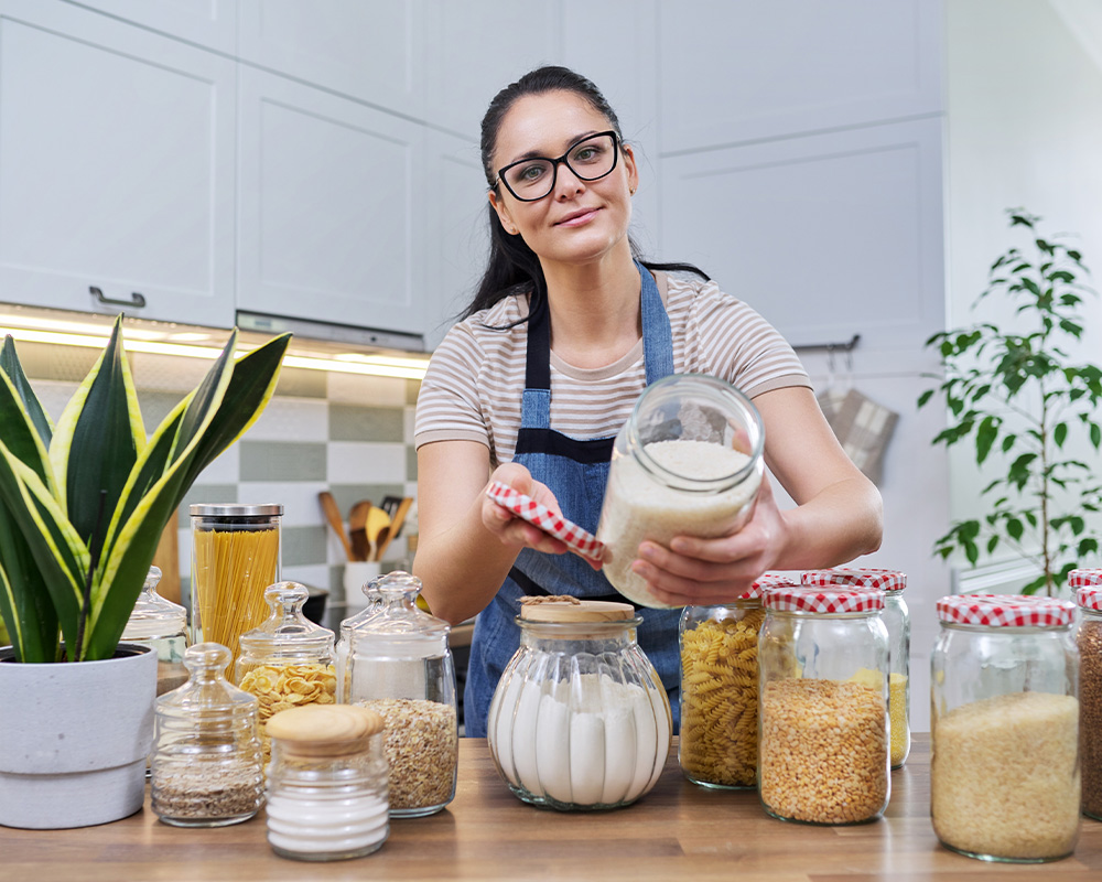 Kobieta w kuchni pokazuje słoiki do przechowywania suchej żywności