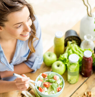 Młoda kobieta w kuchni uśmiecha się, obok warzywa i owoce