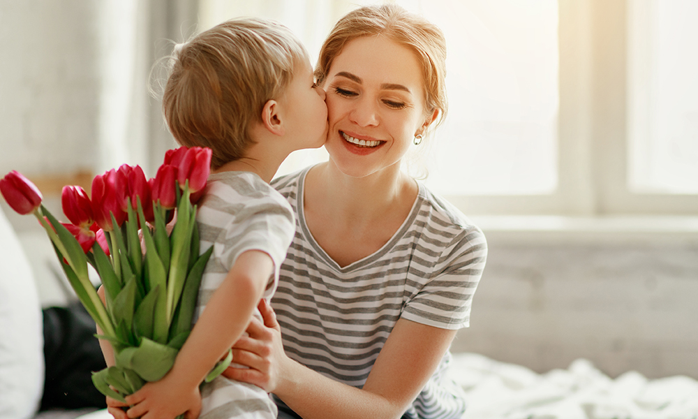 Mały chłopiec daje mamie bukiet tulipanów na dzień matki