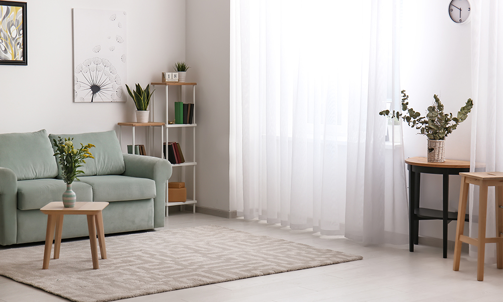 Jasny salon z miętową kanapą, minimalistycznym regałem i roślinami. - tytułowa