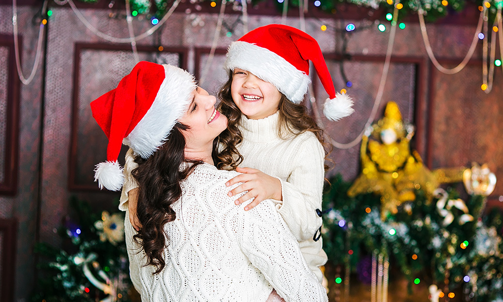 Mama i córka uśmiechają się razem w świątecznych czapach. - tytułowa